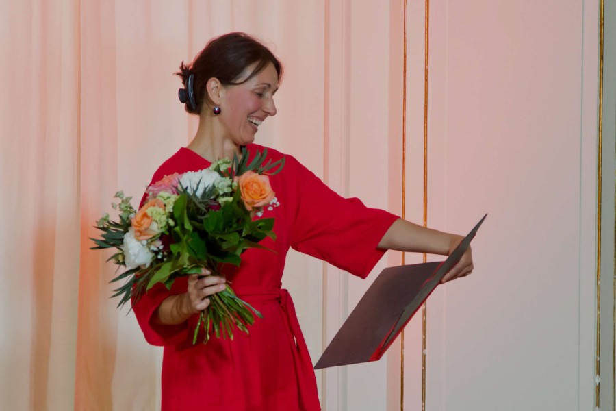 Eine Foto der Preisverleihung. Eine Frau mit Blumenstrauß.